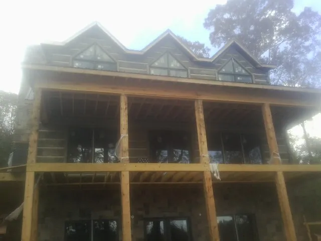Dormers and porch framing on a large log home under construction — Roof Coating work by our crew in Venus